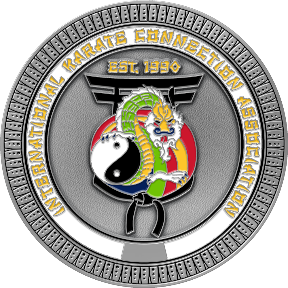 A circular silver-toned medallion or coin featuring the International Karate Connection Association logo and text, with a stylized dragon, yin-yang symbol, and martial arts motifs on a textured gray background.